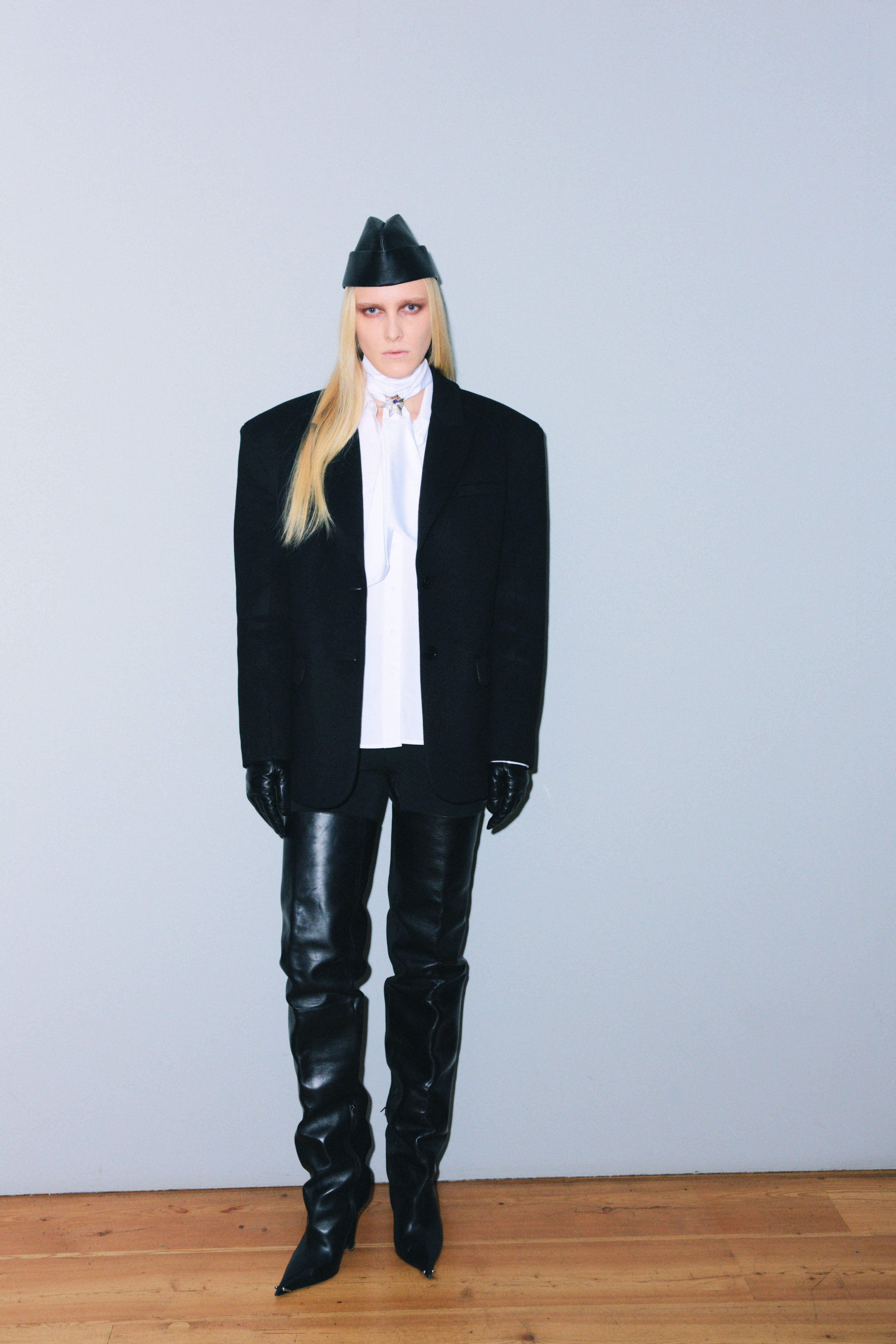 Модель в oversize пиджаке и кожаных обтягивающих брюках, дополненная строгой белой блузкой и оригинальной шляпой.