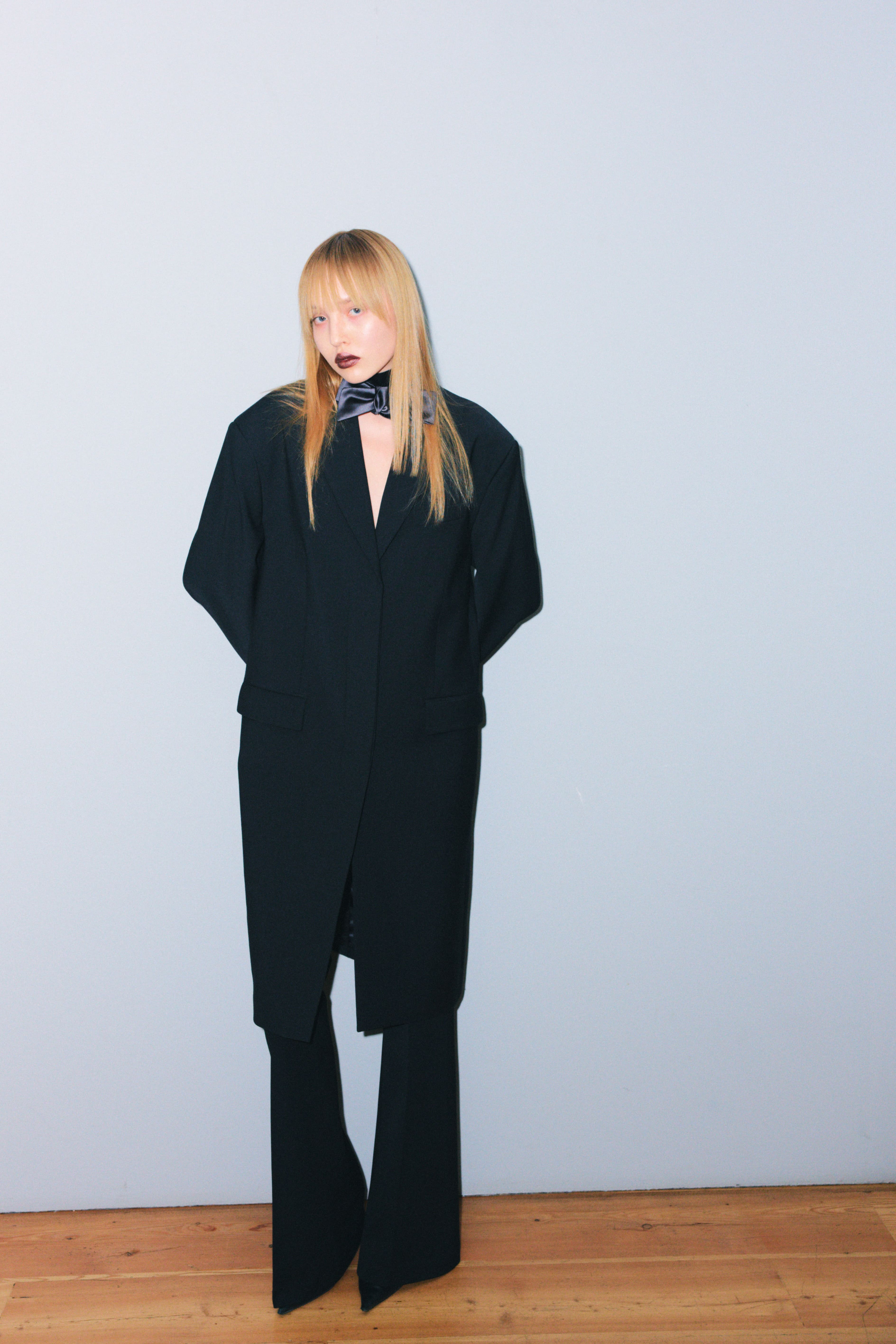 Элегантный черный костюм с глубоким вырезом и широкими брюками, дополненный стильным галстуком, создает атмосферу уверенности и современности....