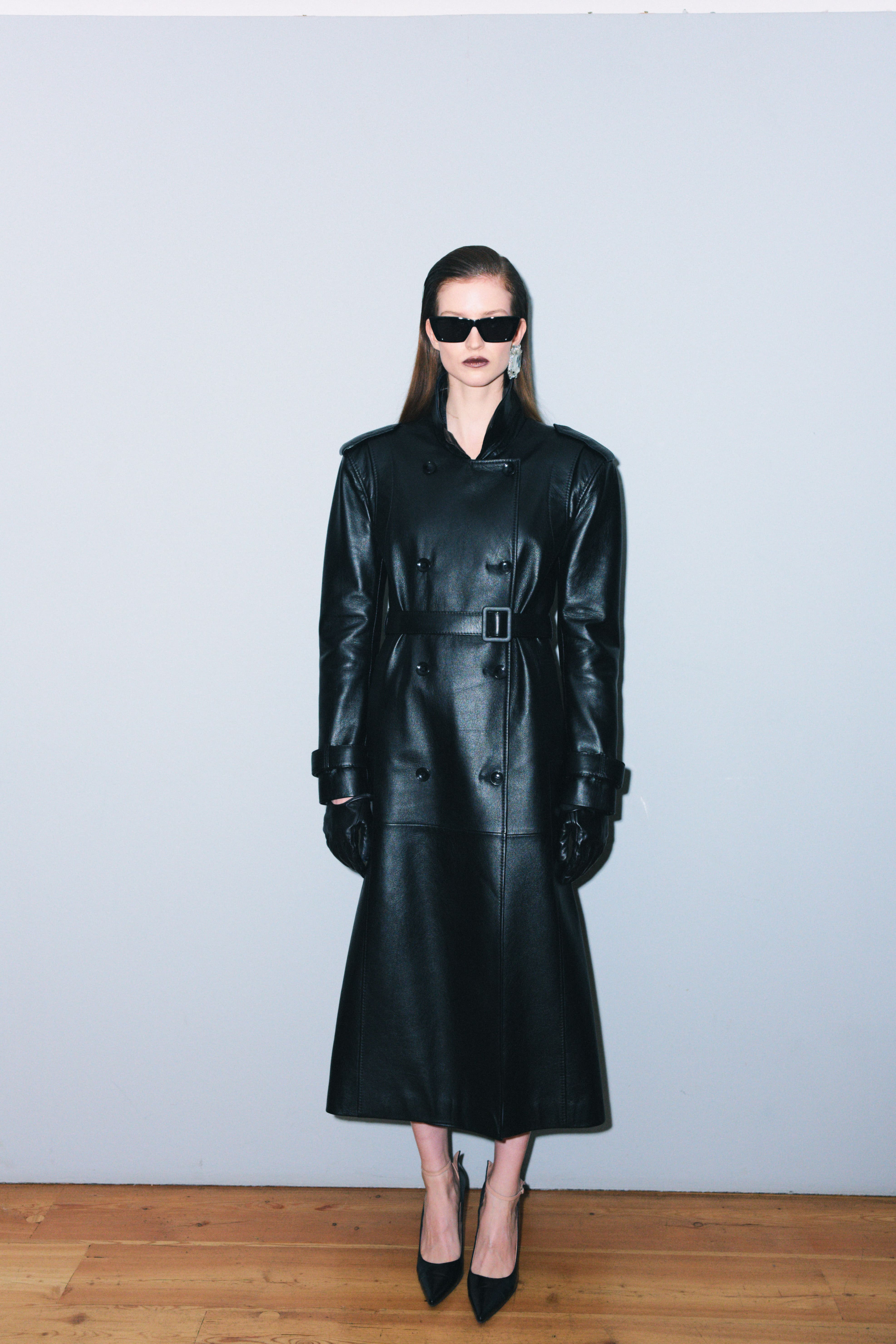 Модель в длинном черном кожаном тренче с поясом, стильные солнцезащитные очки и элегантные туфли на высоком каблуке, осень-зима 2025 от Juliawave