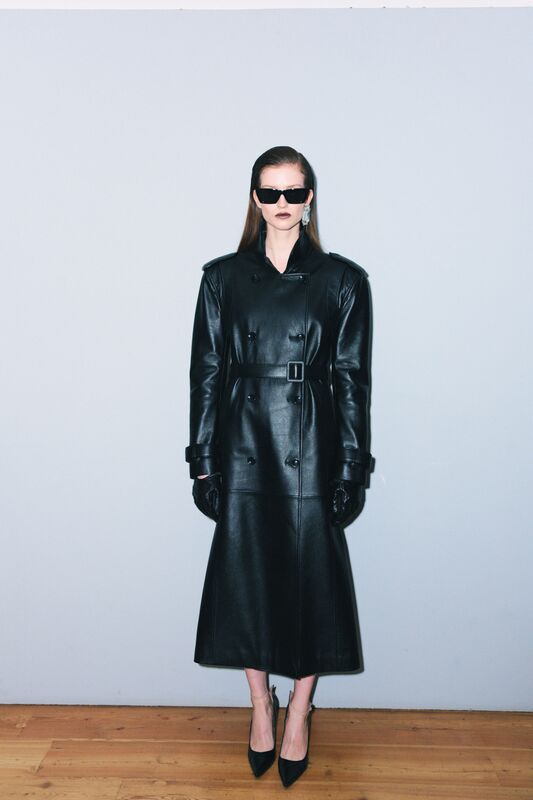 Модель в длинном черном кожаном тренче с поясом, стильные солнцезащитные очки и элегантные туфли на высоком каблуке, осень-зима 2025 от Juliawave
