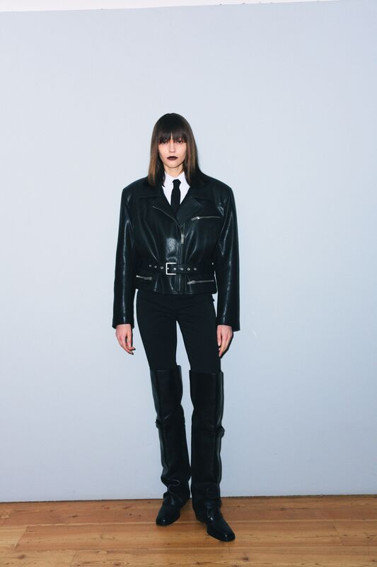 Кожаная куртка с широкими плечами и поясом, черные брюки и высокие сапоги создают строгий, но стильный образ для осени-зимы 2025 от Juliawave.