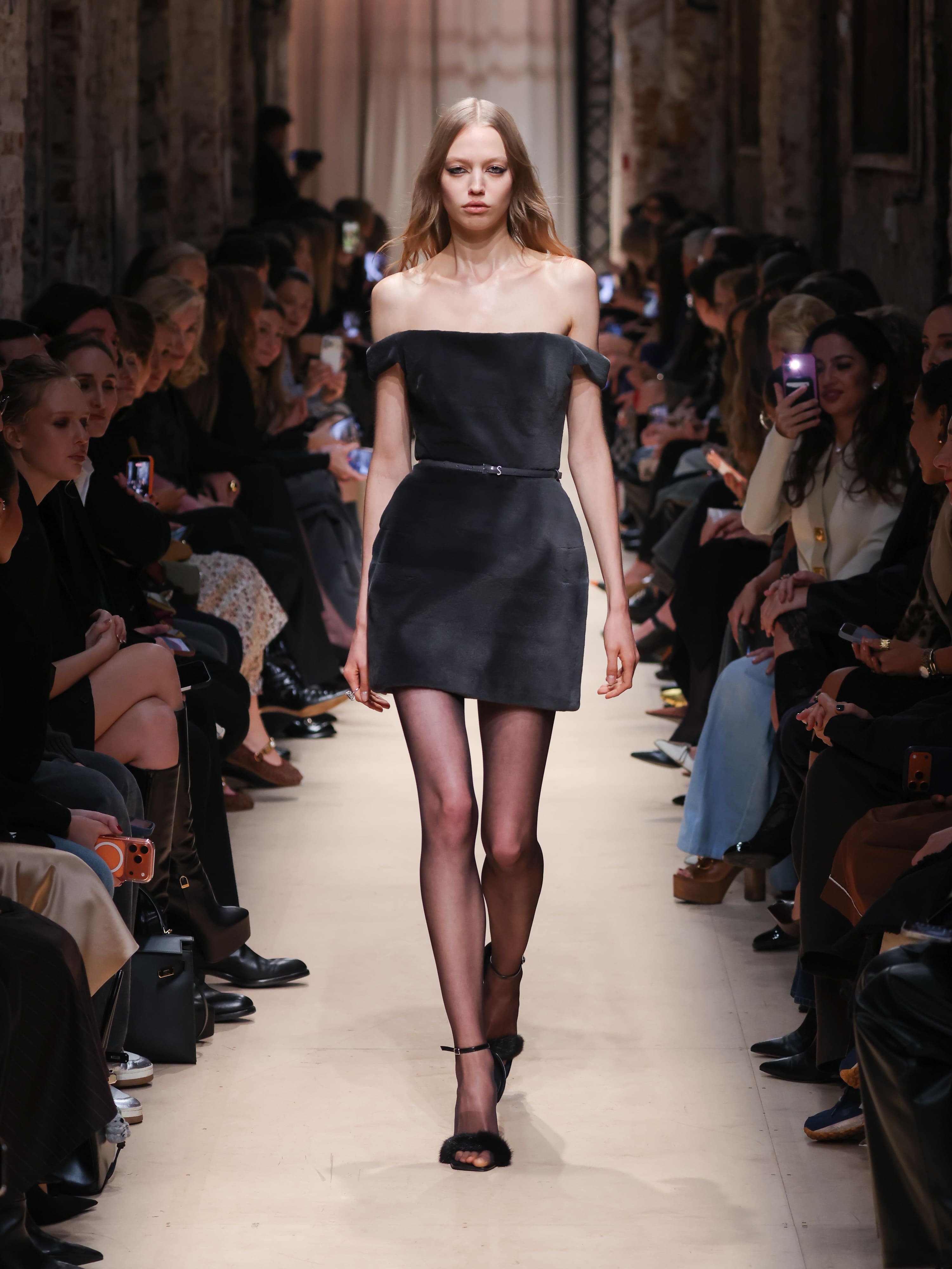Модель в черном мини-платье с открытыми плечами и тонким поясом, эффектно сочетает элегантность и современность на показе Sashaverse осень-зима 2026....