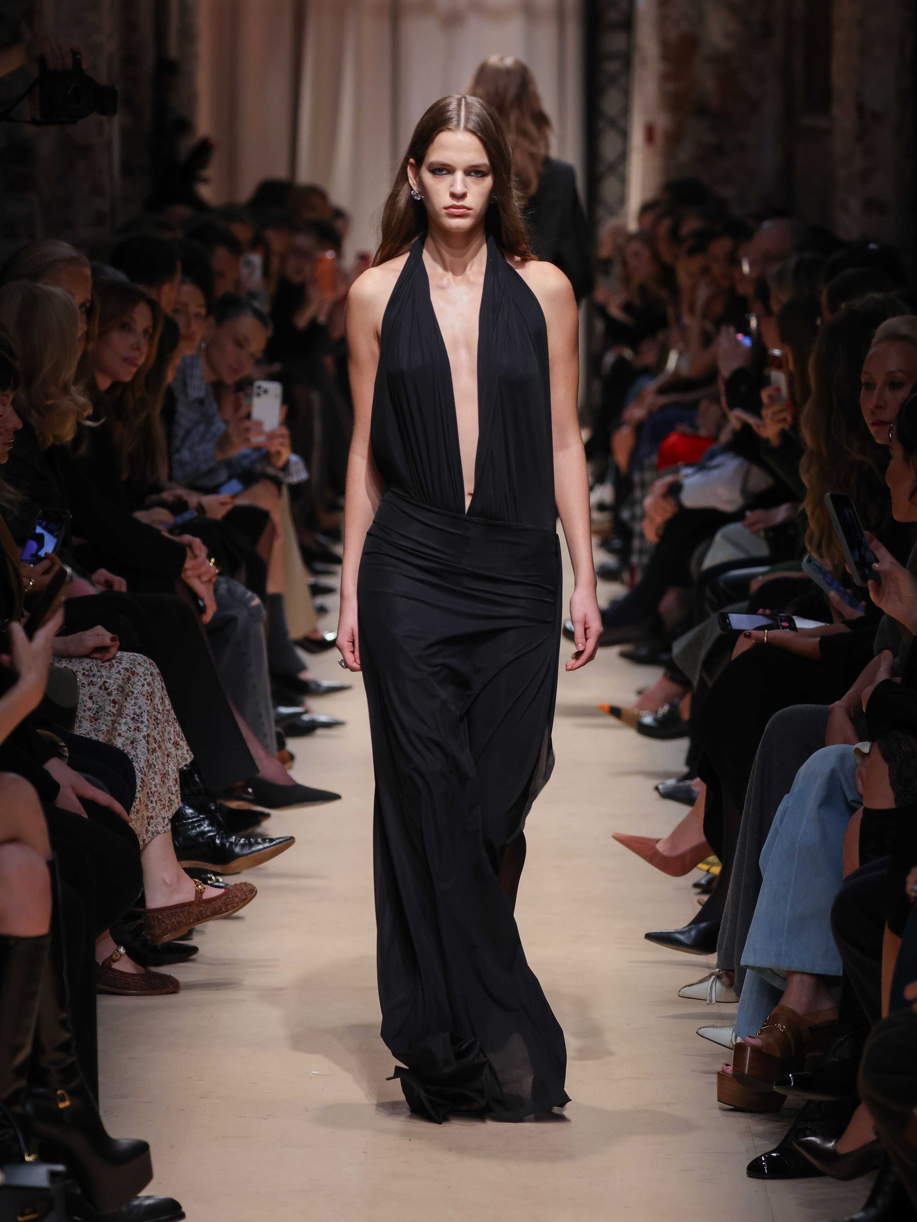 Элегантное черное платье с глубоким вырезом, струящийся силуэт подчеркивает фигуру, создавая атмосферу загадочности на показе Sashaverse осень-зима 2026....