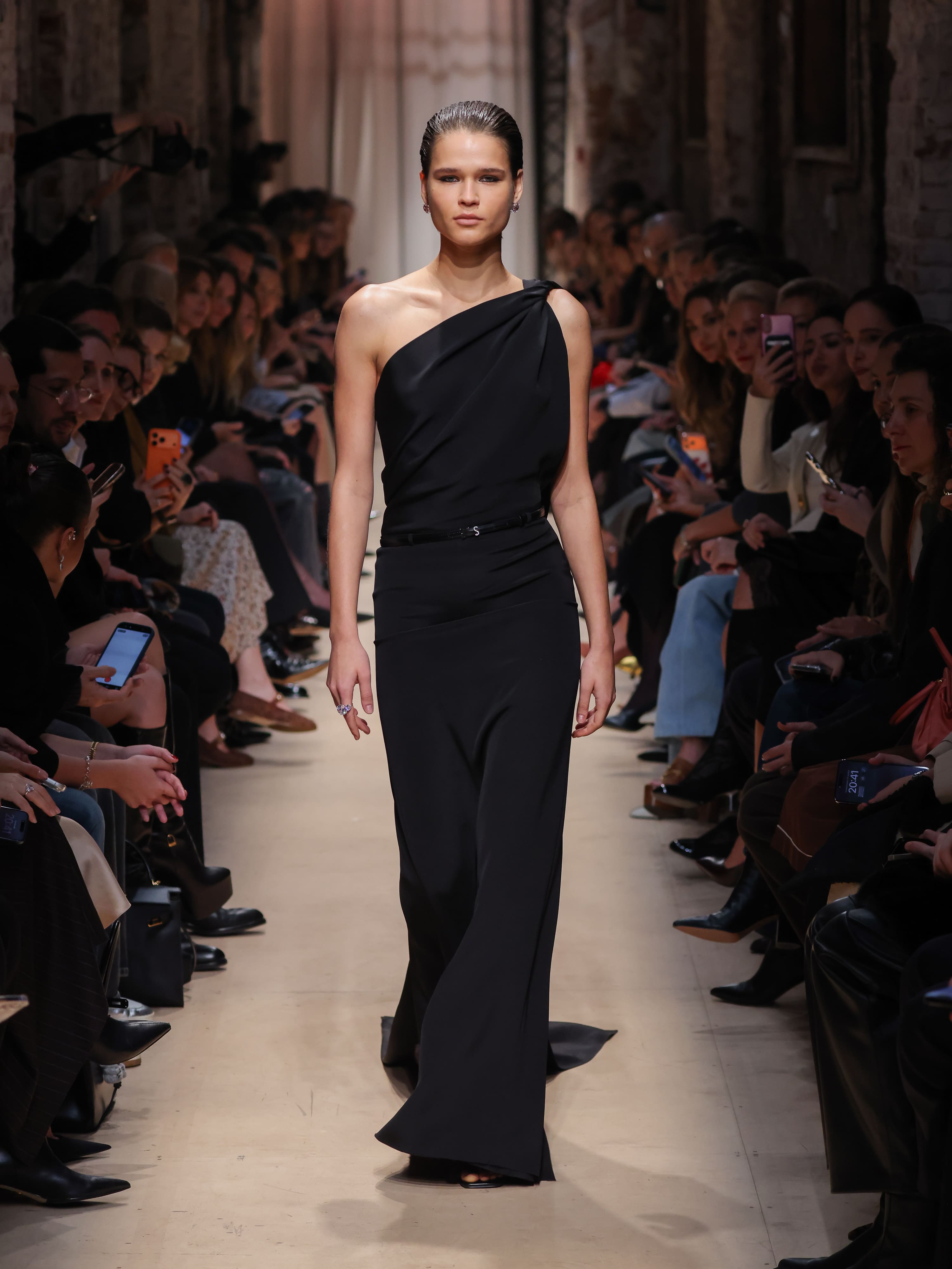 Элегантное черное платье с асимметричным вырезом, подчеркивающее силуэт, создает атмосферу утонченной строгости на показе Sashaverse осень-зима 2026....