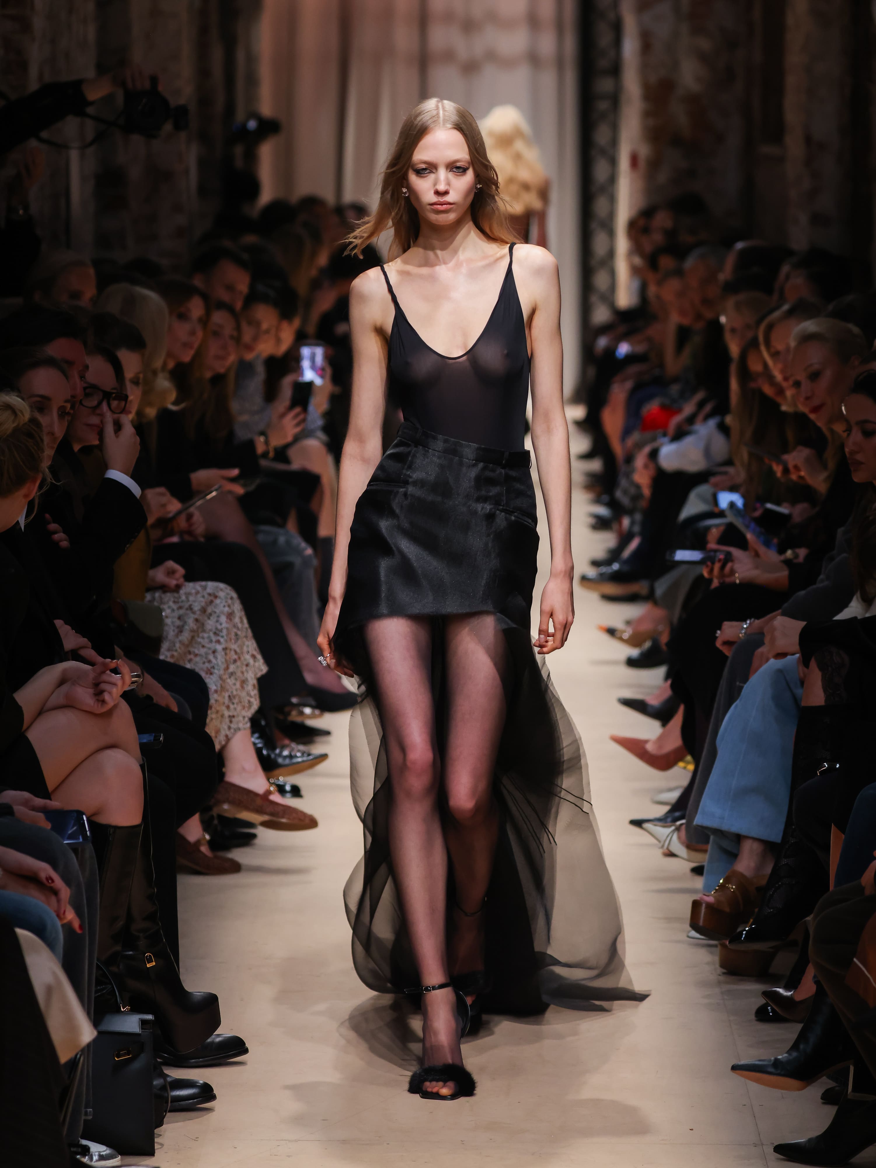 Модель в полупрозрачном топе и юбке с асимметричным подолом из легкой ткани, создающей воздушный силуэт, на показе Sashaverse осень-зима 2026.