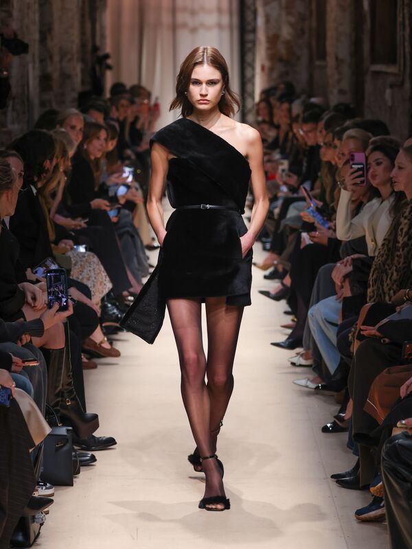 Элегантное черное мини-платье с асимметричным вырезом, подчеркнутое тонким поясом, создает эффектный образ для осени-зимы 2026.