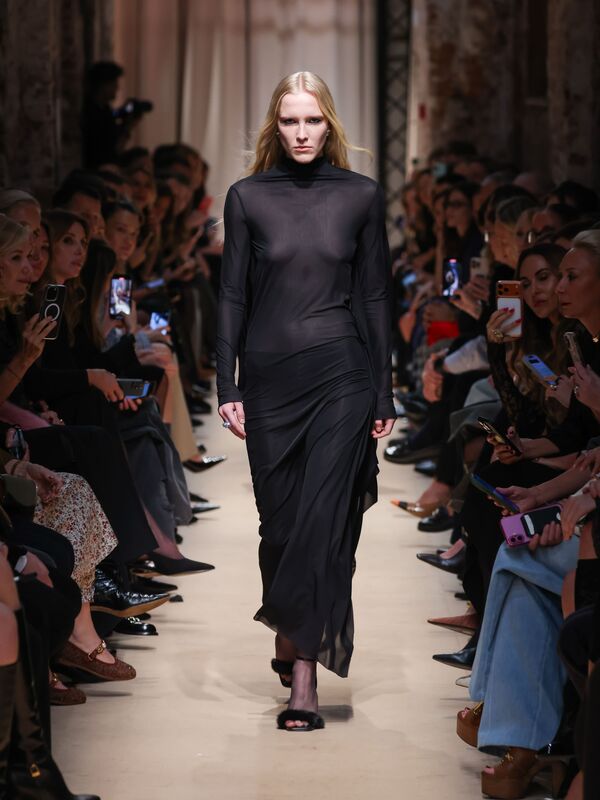 Эфирное черное платье с длинными рукавами и асимметричным подолом, создающее загадочную атмосферу на показе Sashaverse осень-зима 2026.