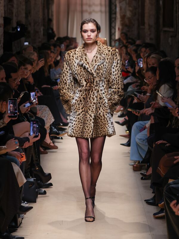 Модель в роскошном леопардовом пальто от Sashaverse, осень-зима 2026, уверенно шагает по подиуму, привлекая внимание зрителей.