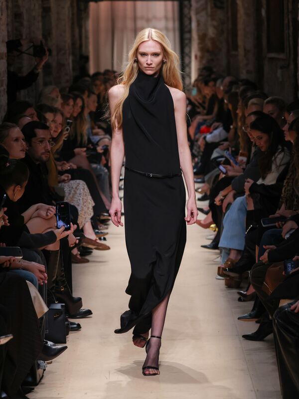 Элегантное черное платье с драпировкой и разрезом, подчеркивающее силуэт, создает атмосферу утонченной роскоши на показе Sashaverse.