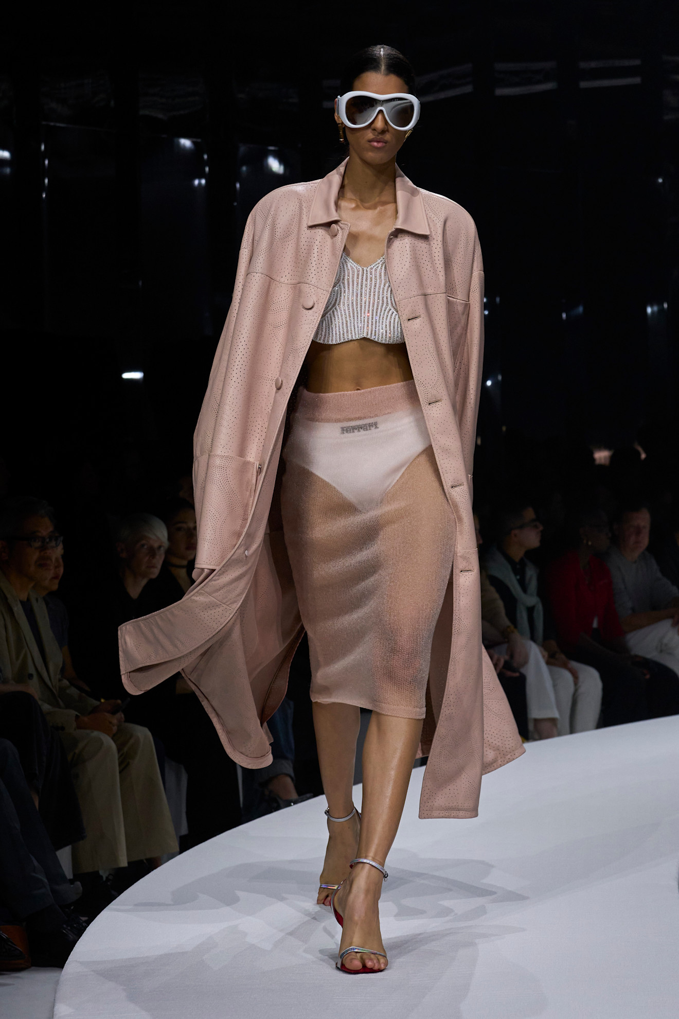 Модель в нежно-розовом тренче и полупрозрачной юбке демонстрирует утонченность и современный стиль на показе Ferrari SS 2024.