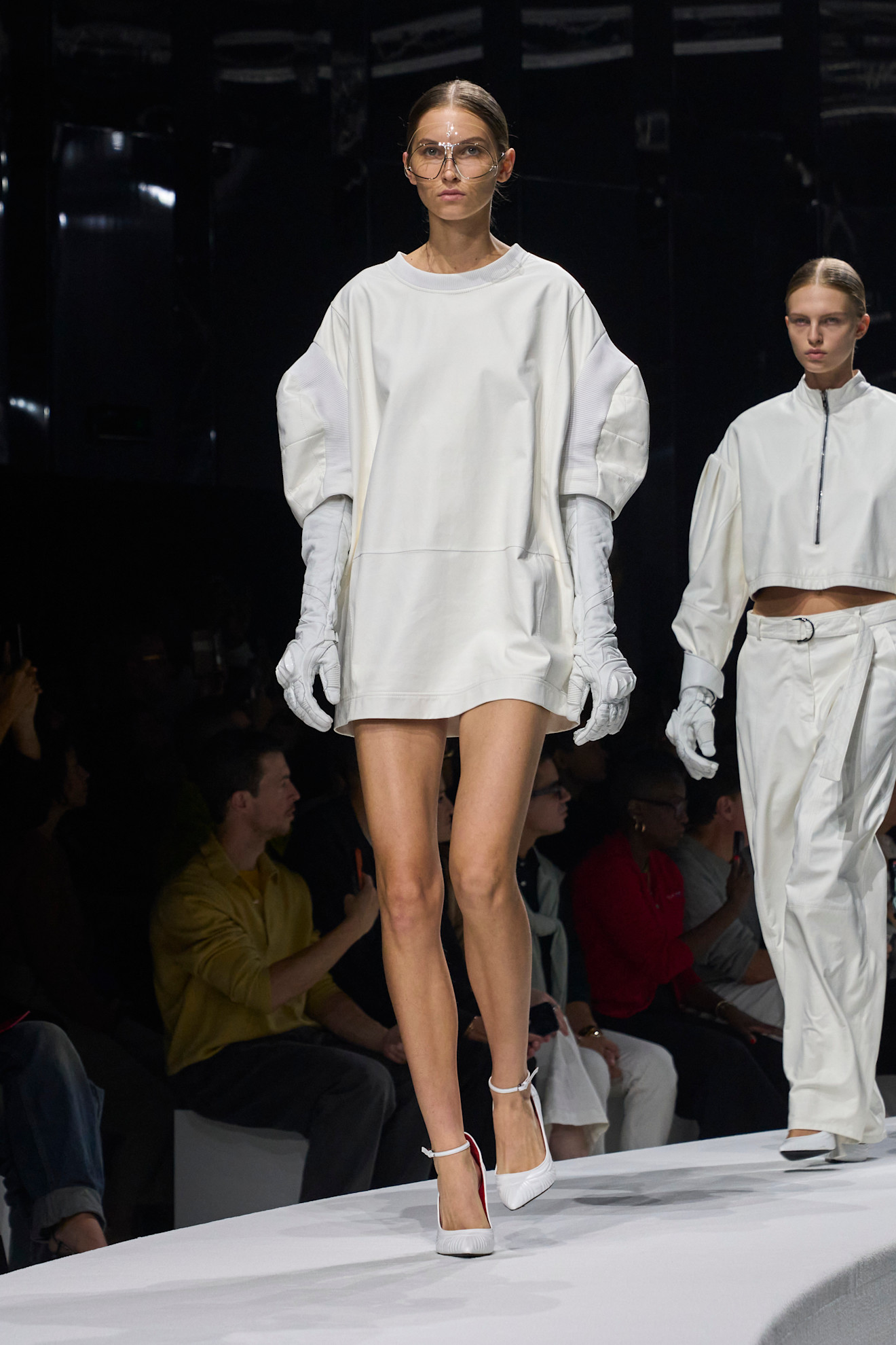 Модель в объемном белом платье с рукавами-буфами и длинных перчатках, завершает образ стильными белыми туфлями на высоком каблуке.