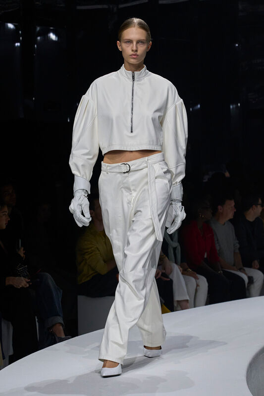 Модель в белом комплекте с объемными рукавами и элегантными перчатками, создающая атмосферу современного минимализма на показе Ferrari весна/лето 2024...