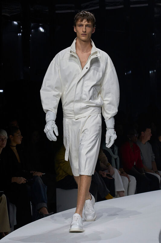 Мужская коллекция Ferrari весна/лето 2024: объемная белая куртка с короткими шортами, стильный спортивный образ с перчатками и обувью.