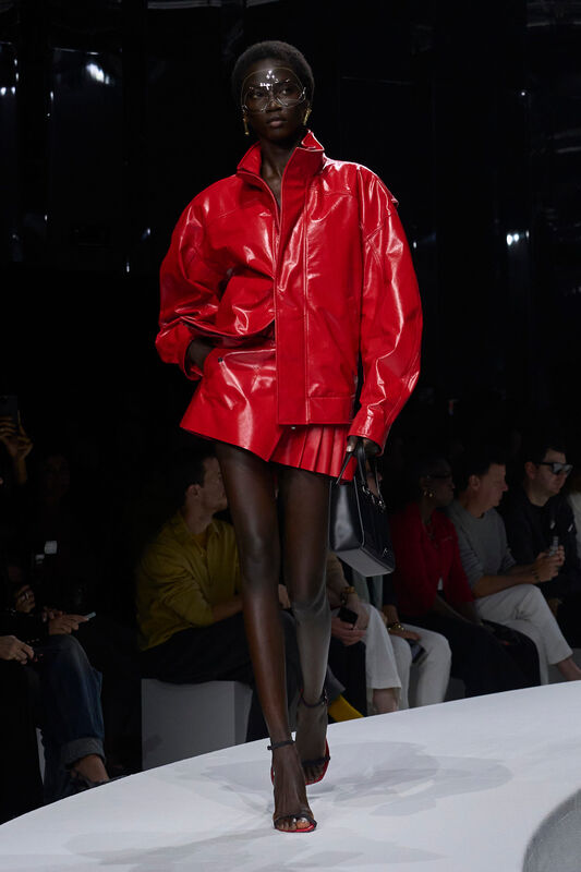 Яркий красный кожаный комплект с объемной курткой и мини-юбкой, дополненный стильными аксессуарами и эффектными сандалиями.