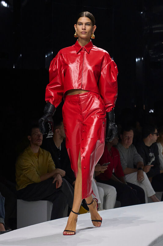 Яркий красный комплект из лакированной кожи с объемными рукавами и разрезом на юбке, дополненный стильными перчатками и босоножками.