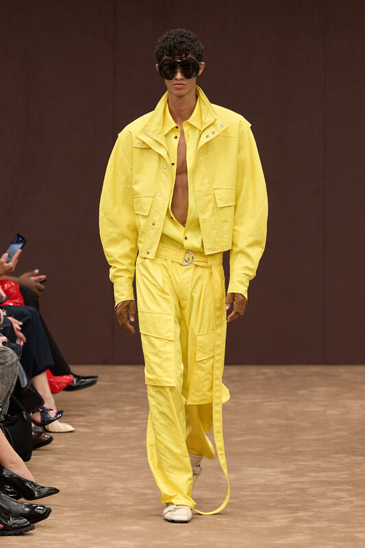 Яркий желтый комплект из легкой ткани с объемной курткой и широкими брюками, дополненный эффектными очками, создает атмосферу летнего шика....