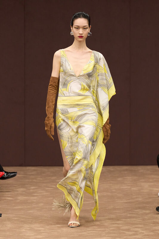 Лёгкое платье с абстрактным желтым принтом и глубоким вырезом, дополненное замшевыми перчатками и элегантными босоножками.