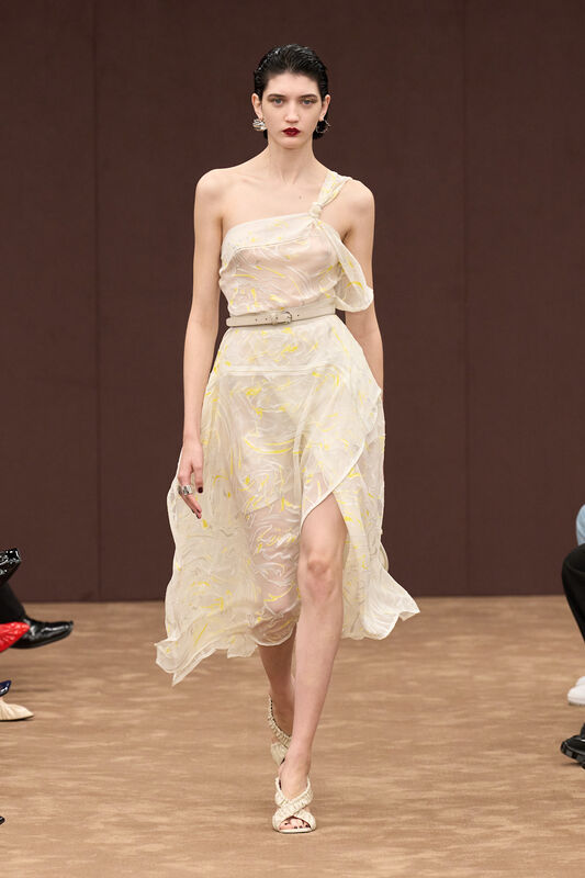 Легкое полупрозрачное платье с асимметричным вырезом, украшенное нежным узором в желтых тонах, создает романтичный образ для весны-лето 2025 от Ferrari....