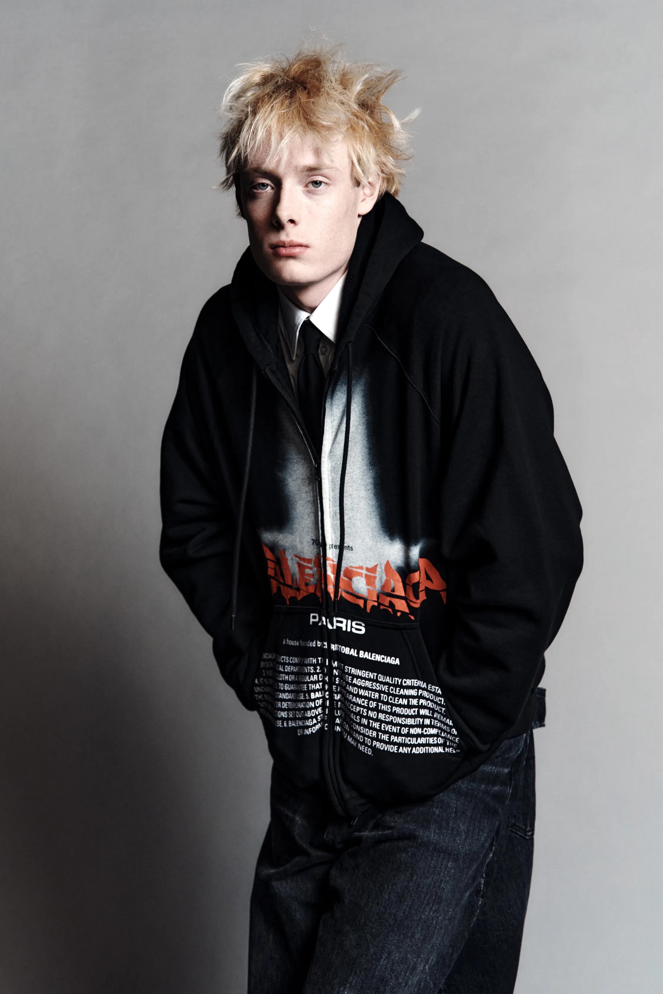 Модель в черном худи с ярким принтом и джинсах, с небрежной прической, создает атмосферу уличного стиля