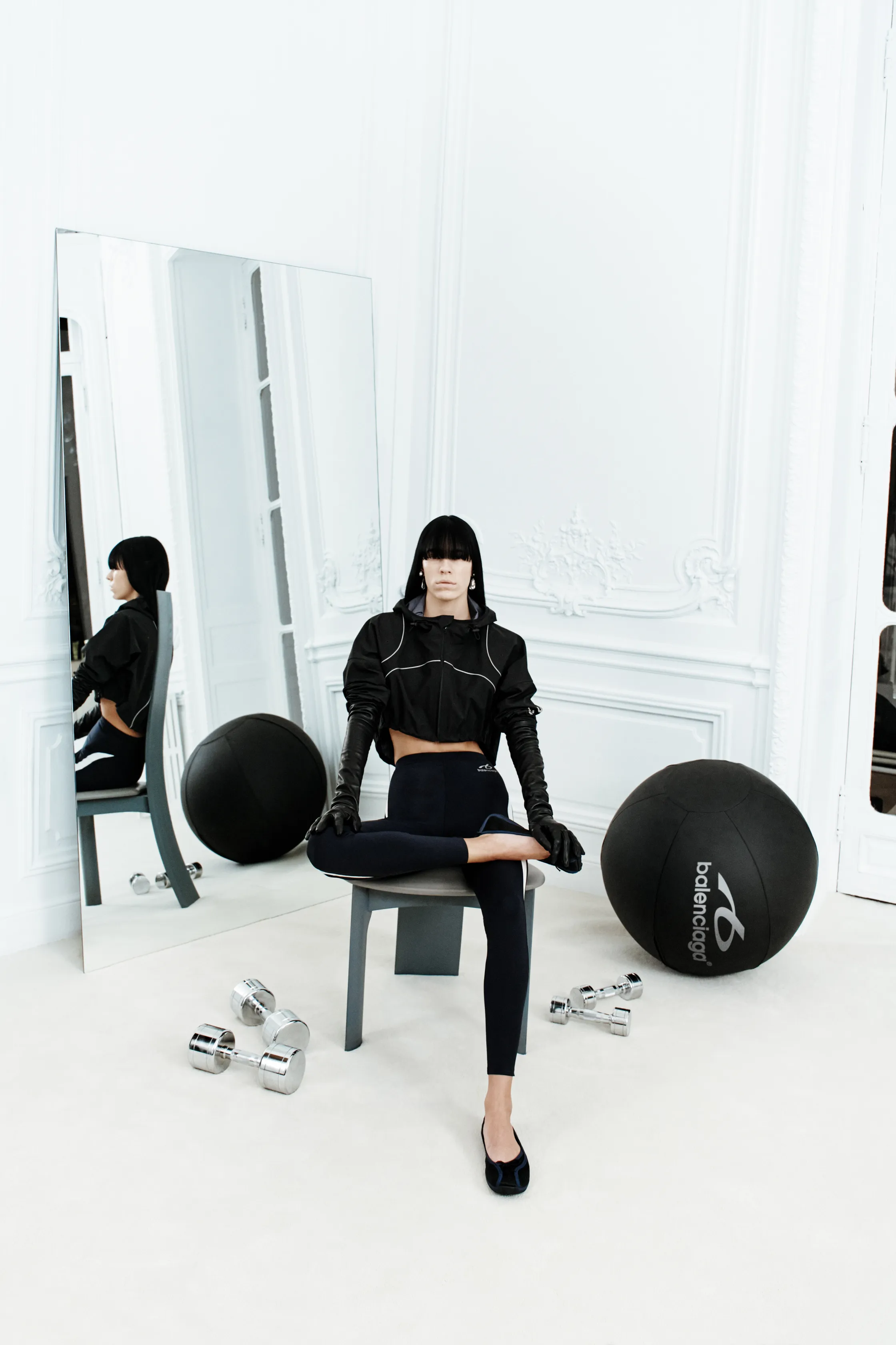 Обтягивающий черный топ и леггинсы с контрастными вставками, создающие спортивный образ в минималистичном интерьере