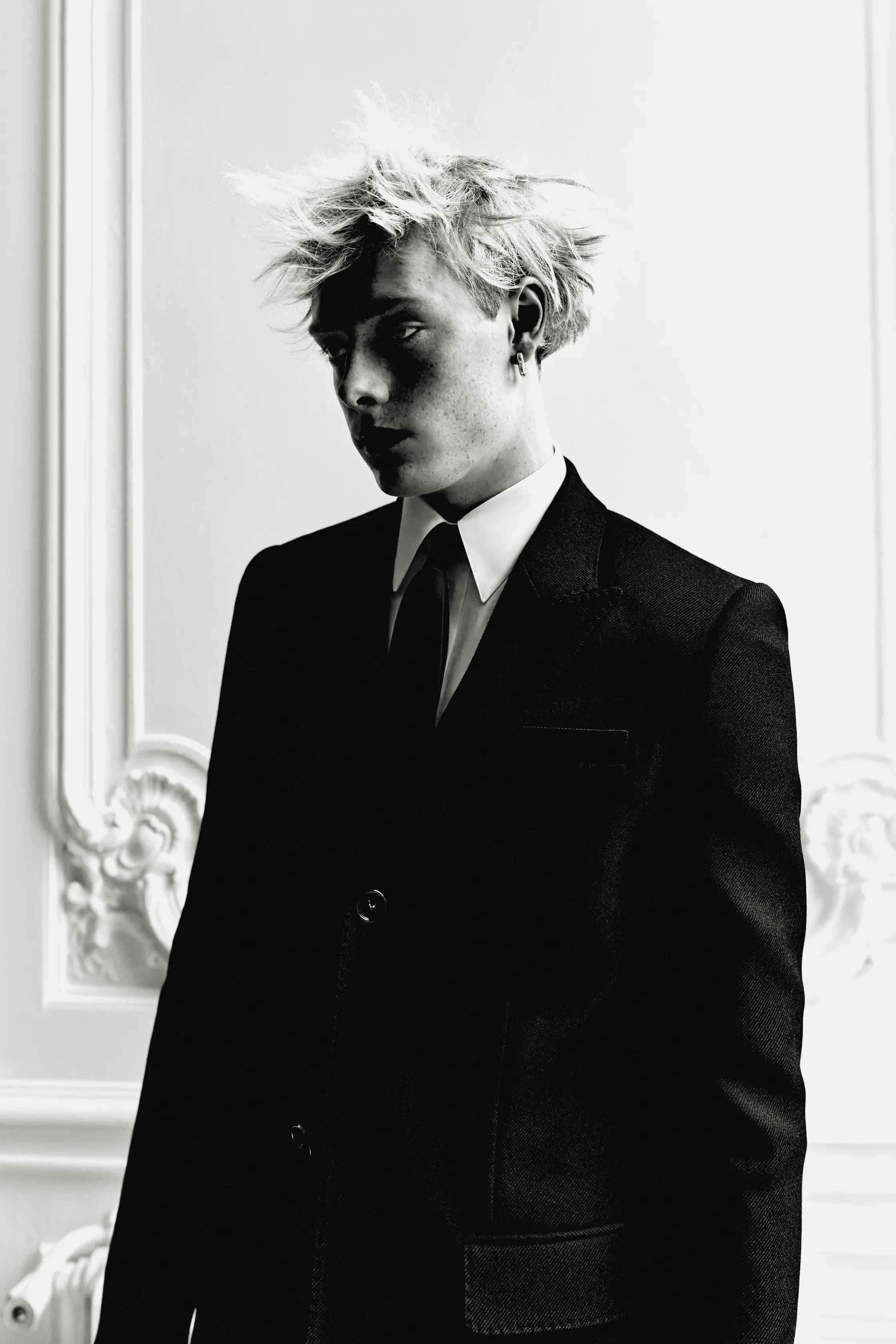 Черный смокинг с классическим воротником и небрежной прической, передающий атмосферу загадочности и элегантности