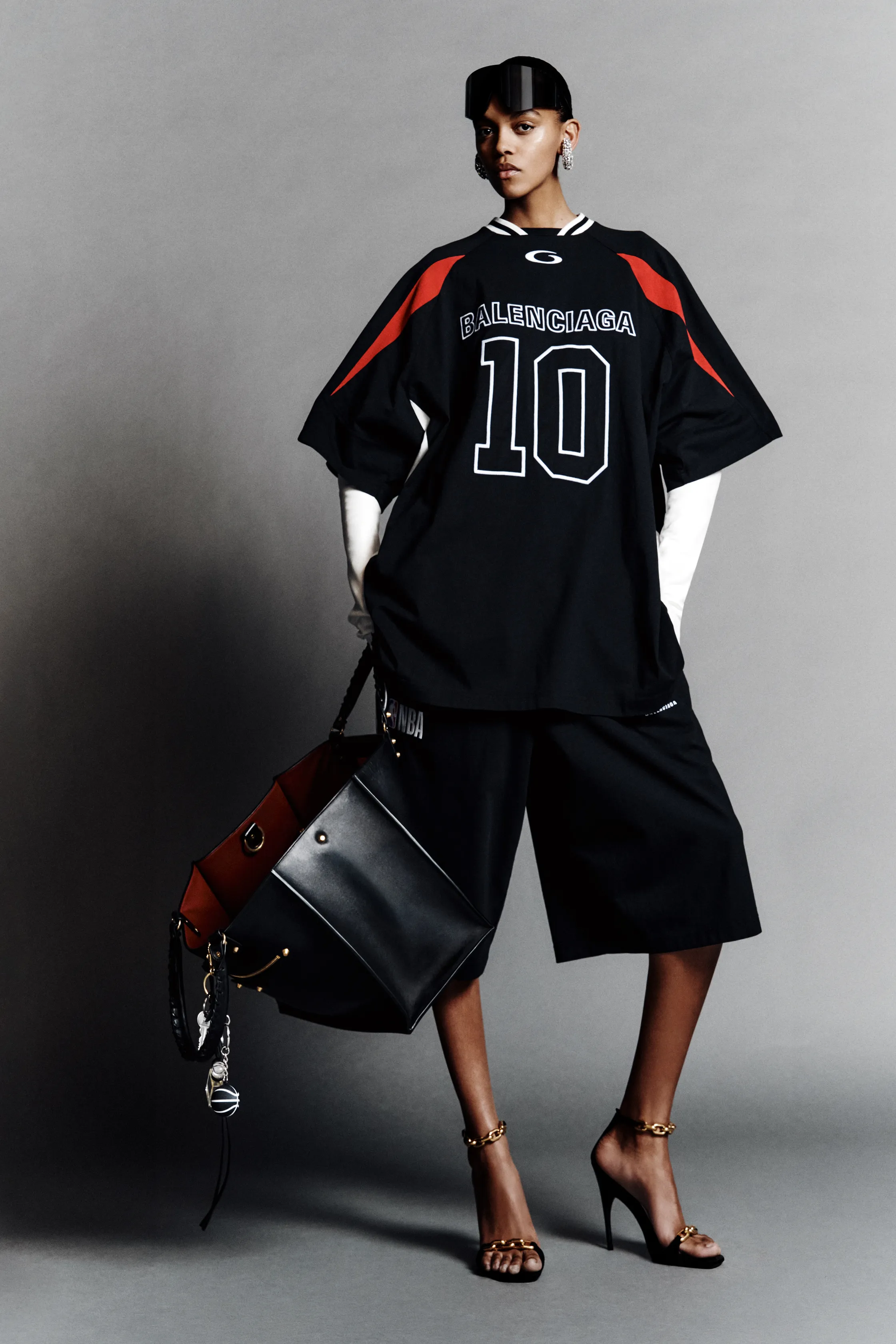 Спортивная футболка с номером и широкие шорты в черно-красной гамме, дополненные стильной сумкой и высокими каблуками