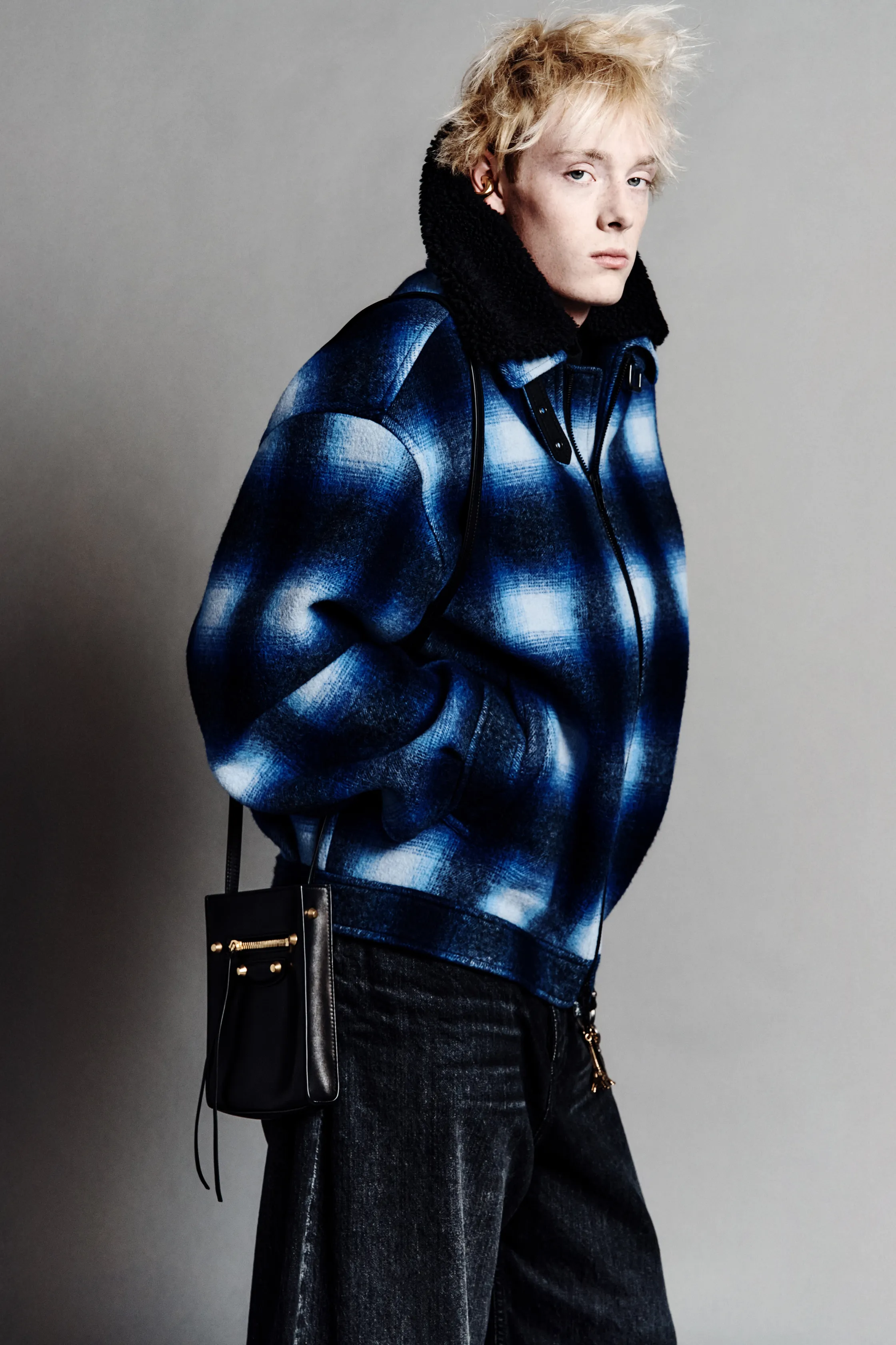 Пуховик в клетку с яркими синими оттенками и черной сумкой добавляют дерзости в образ, акцентируя внимание на текстуре