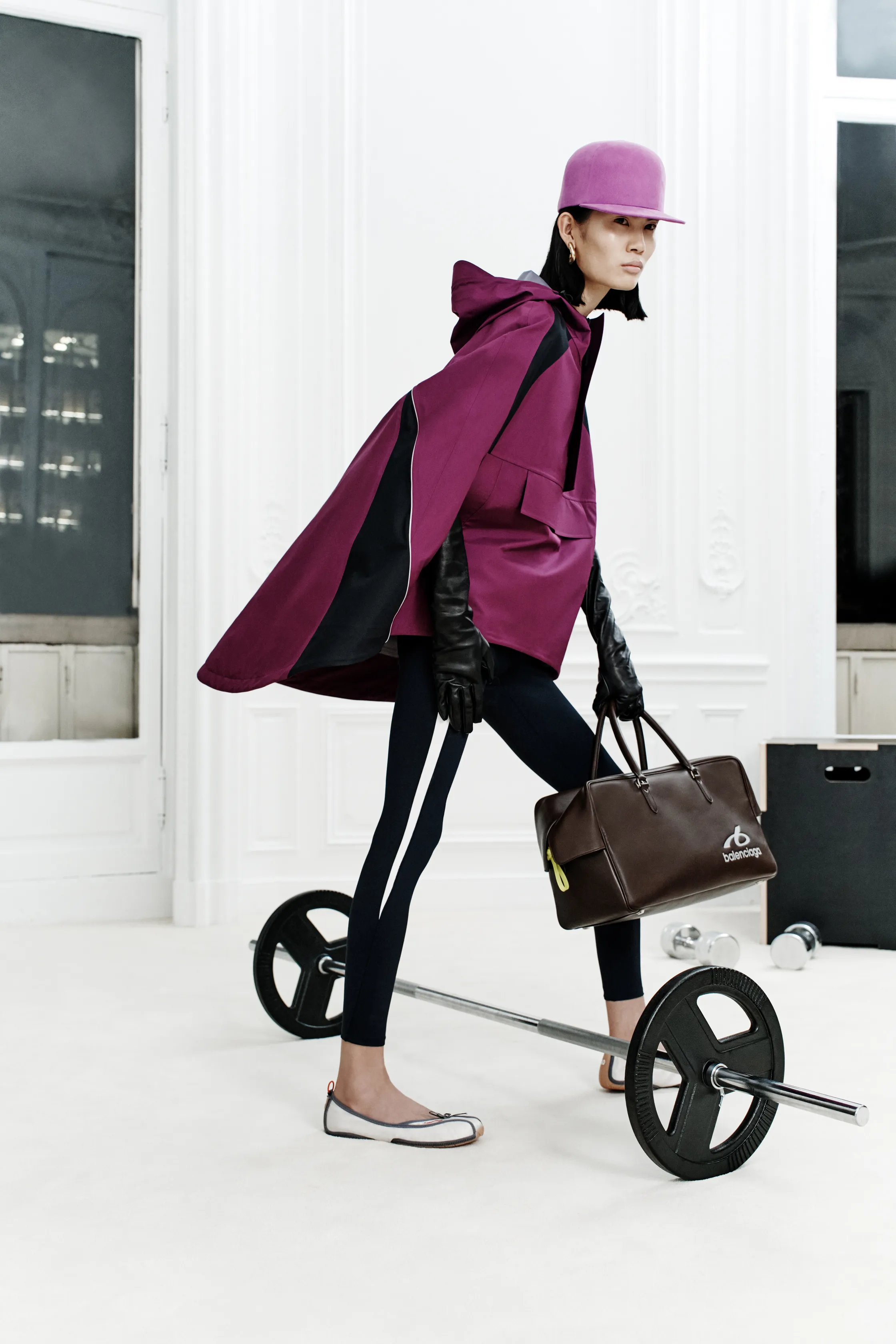 Плащ насыщенного пурпурного цвета с черными вставками, леггинсы и стильная сумка создают динамичный спортивный образ