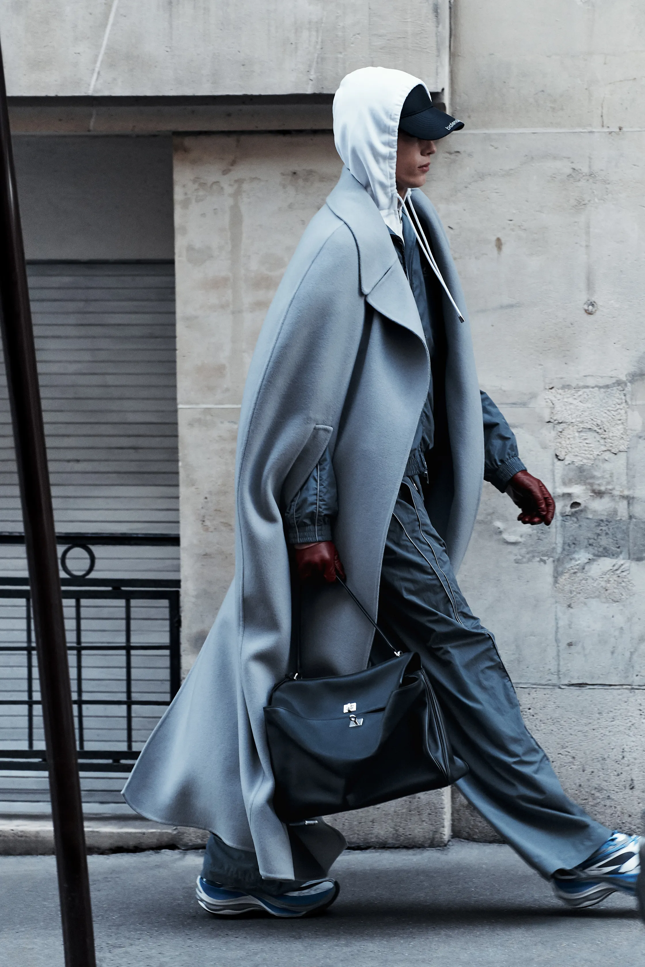 Элегантный серый плащ с капюшоном и спортивный костюм, дополненные черной сумкой, создают современный городской стиль