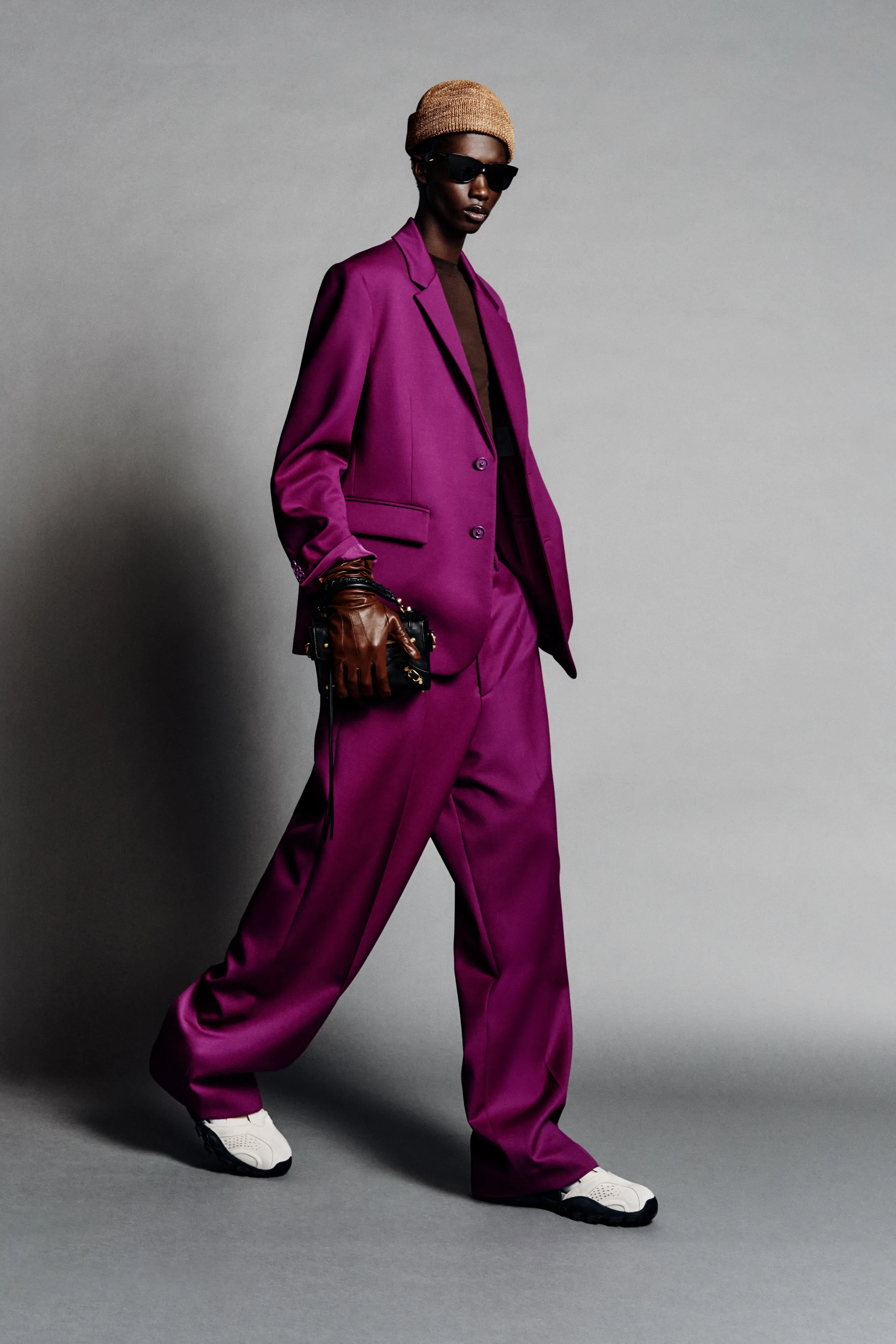 Яркий пурпурный костюм с широкими брюками и кроссовками, дополненный стильной шапкой и солнцезащитными очками