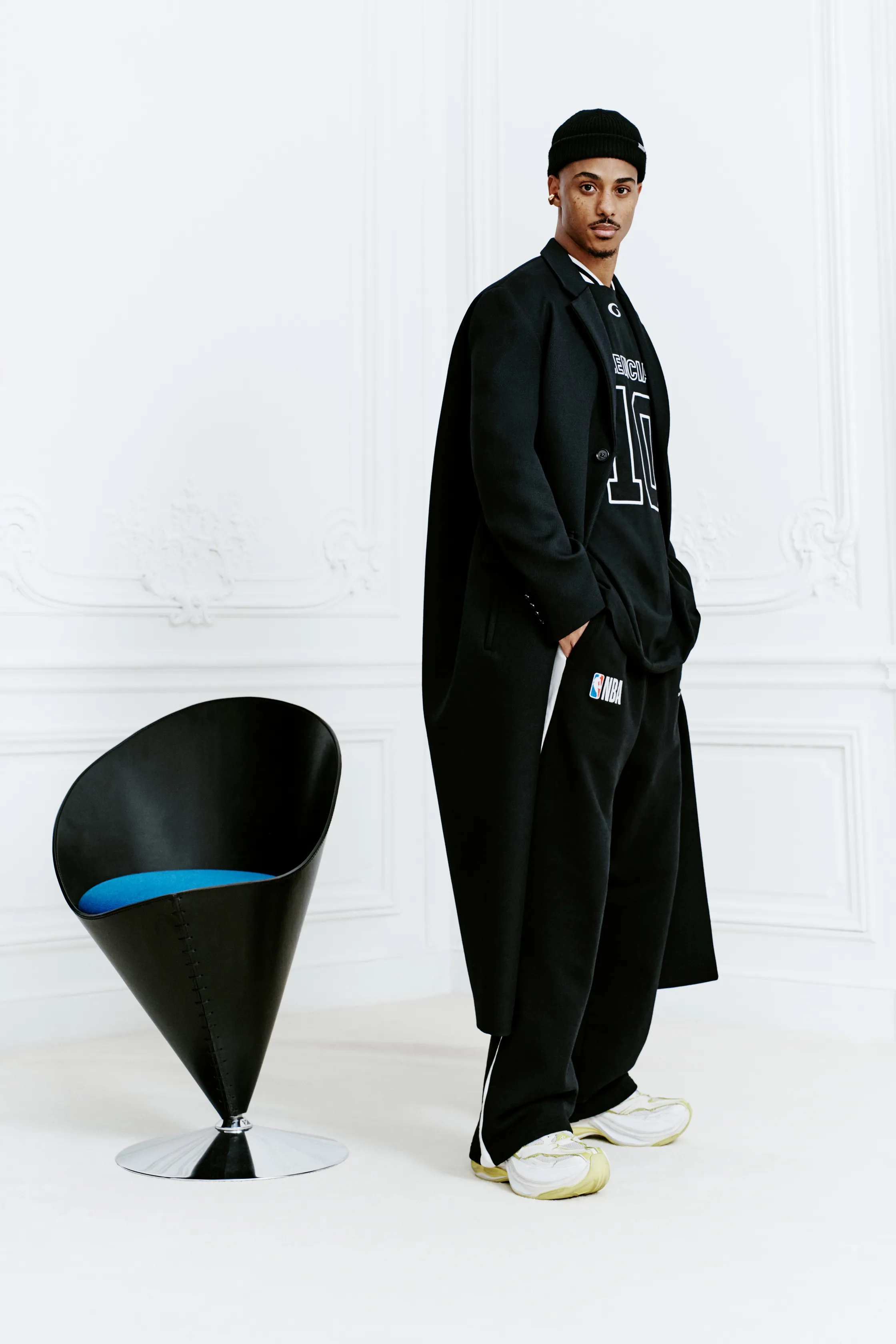 Стильный черный наряд с спортивным акцентом, длинный плащ и кроссовки, подчеркивающие современный городской стиль