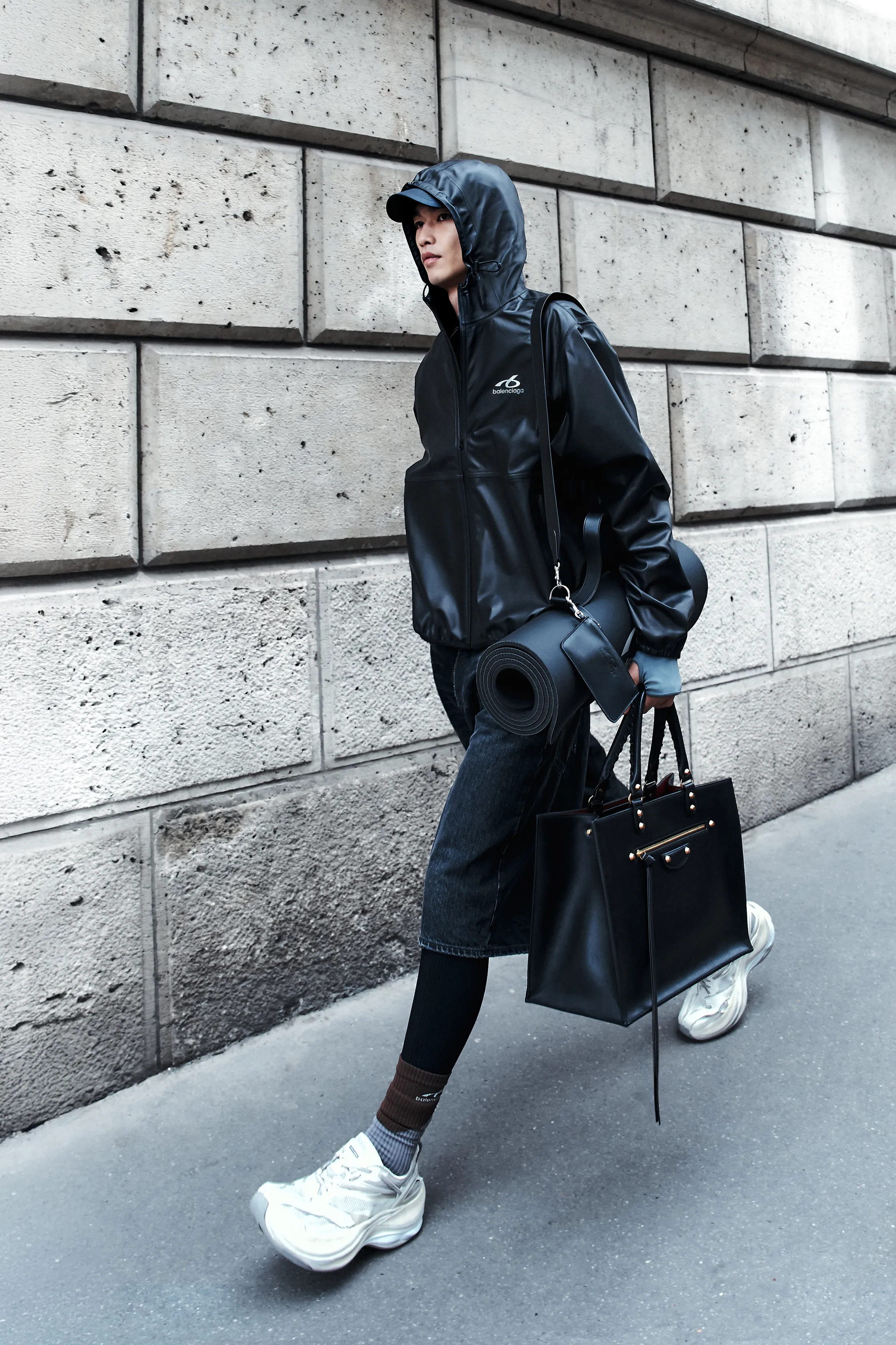 Лаконичная черная куртка с капюшоном и джинсовыми шортами, дополненная спортивной обувью и большой сумкой