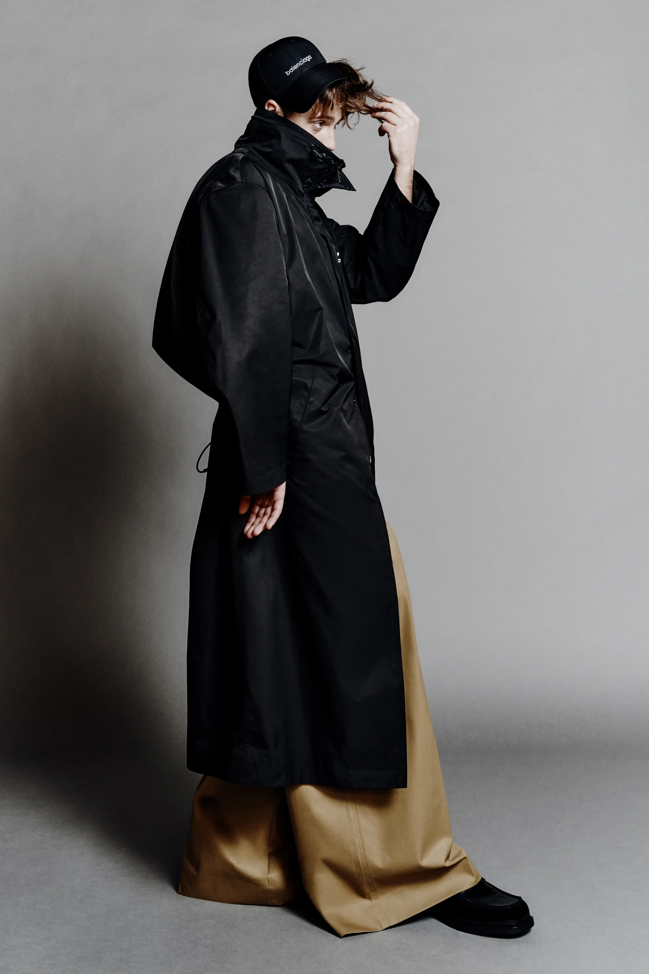 Черный дождевик с широкими рукавами и светлыми брюками, подчеркивающий контрастные текстуры и силуэт