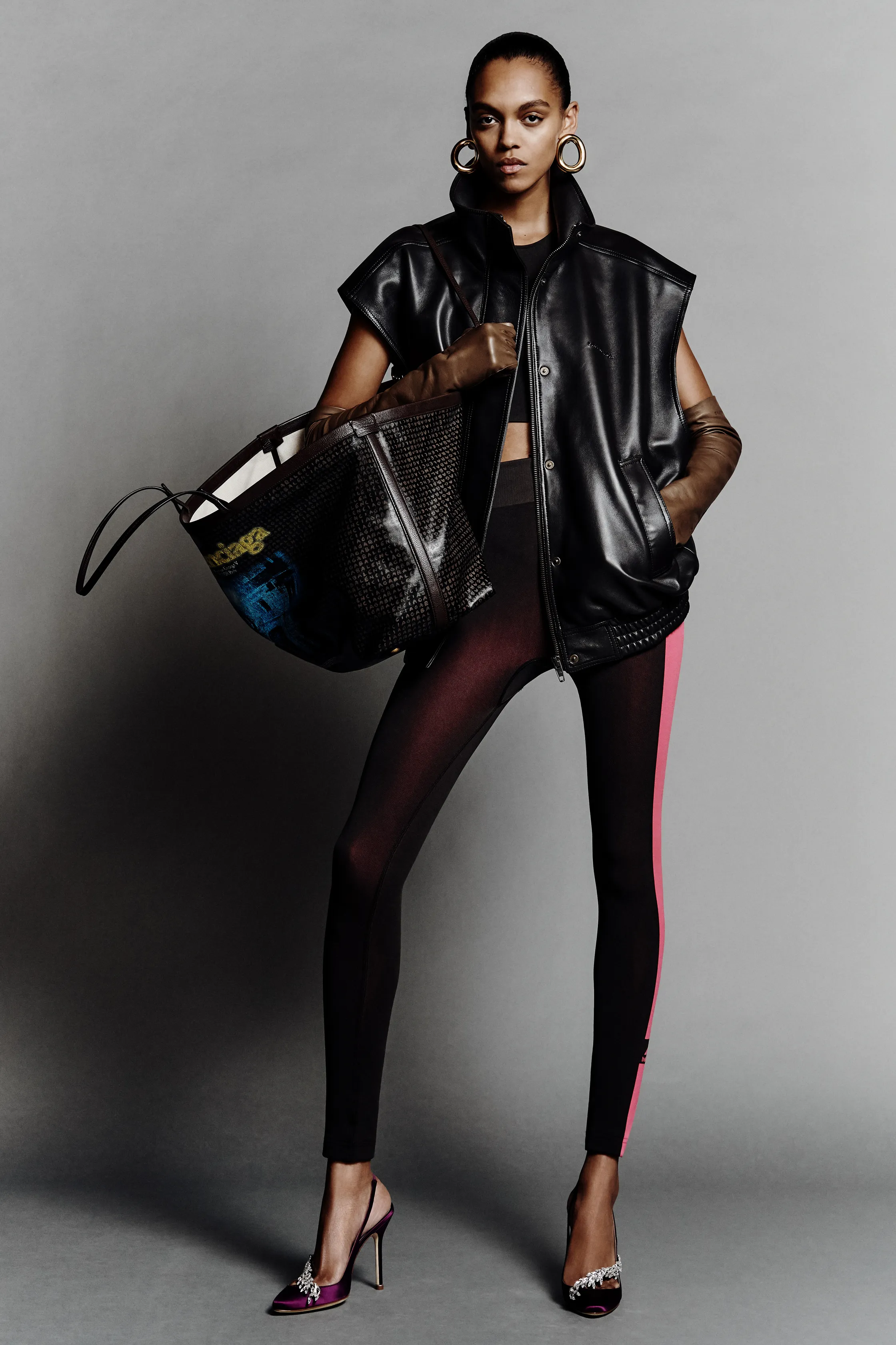 Объемный черный кожаный жилет в сочетании с облегающими леггинсами и яркими туфлями, создающими стильный контраст