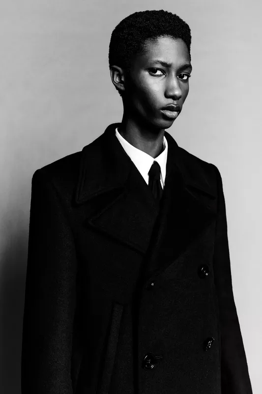 Портрет в черном пальто с классическим воротником и строгой белой рубашкой, передающий атмосферу уверенности и элегантности