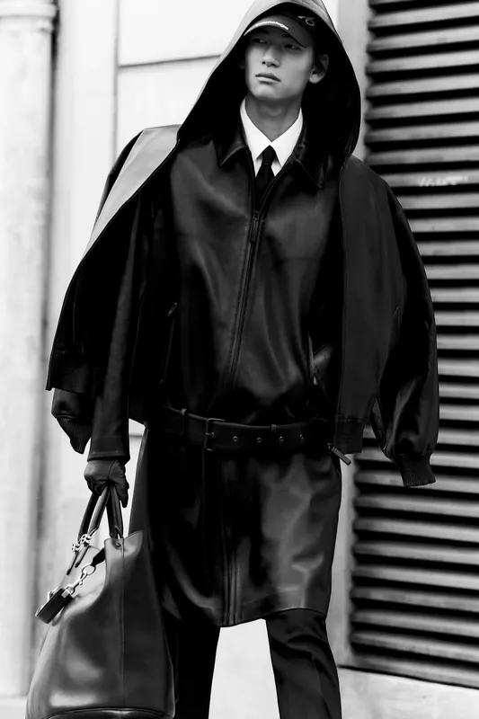 Черное кожаное пальто с капюшоном и строгий галстук, создающие эффектный образ в монохромной палитре.