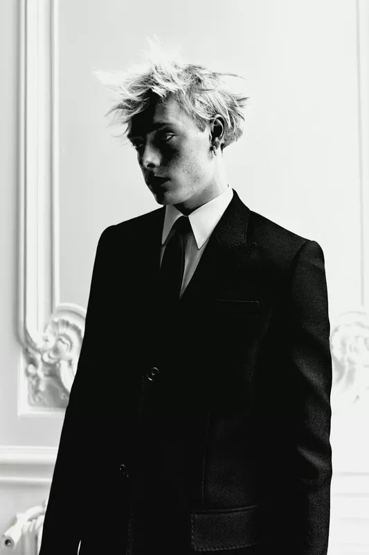 Черный смокинг с классическим воротником и небрежной прической, передающий атмосферу загадочности и элегантности