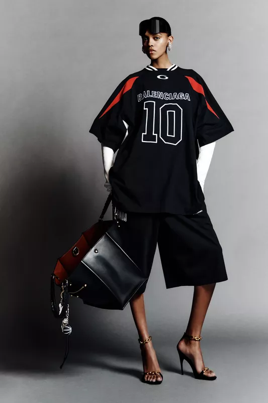 Спортивная футболка с номером и широкие шорты в черно-красной гамме, дополненные стильной сумкой и высокими каблуками