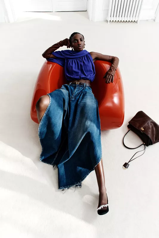 Ярко-фиолетевый топ и асимметричная джинсовая юбка создают смелый образ, дополненный длинными перчатками и элегантными туфлями