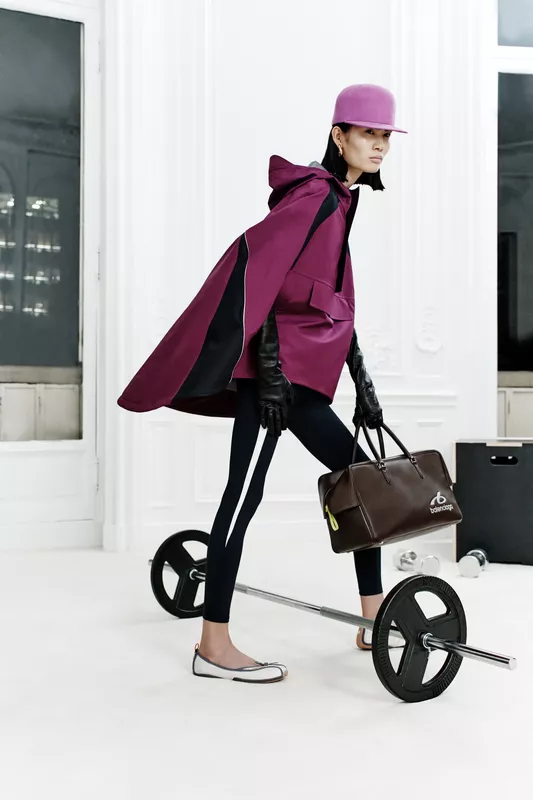 Плащ насыщенного пурпурного цвета с черными вставками, леггинсы и стильная сумка создают динамичный спортивный образ