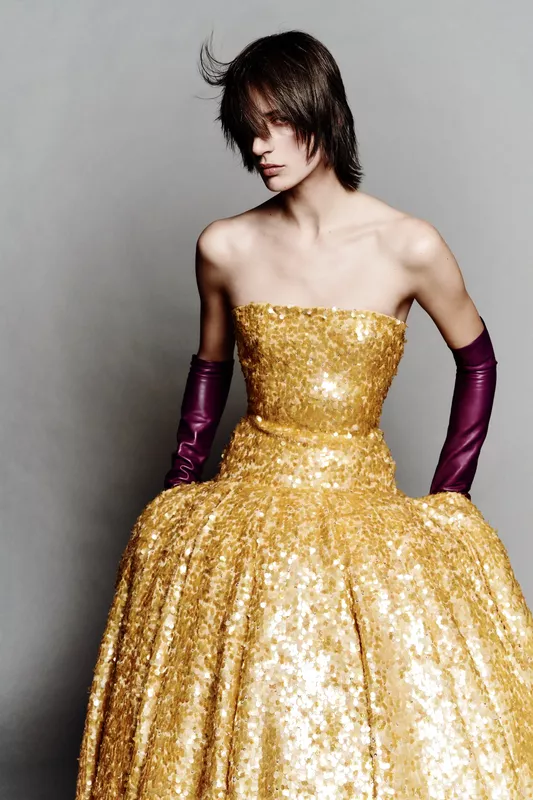 Роскошное золотое платье с блестками, дополненное длинными фиолетовыми перчатками, создающее эффектный образ на фоне нейтрального фона