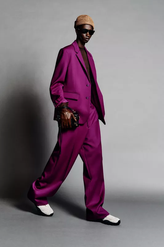 Яркий пурпурный костюм с широкими брюками и кроссовками, дополненный стильной шапкой и солнцезащитными очками