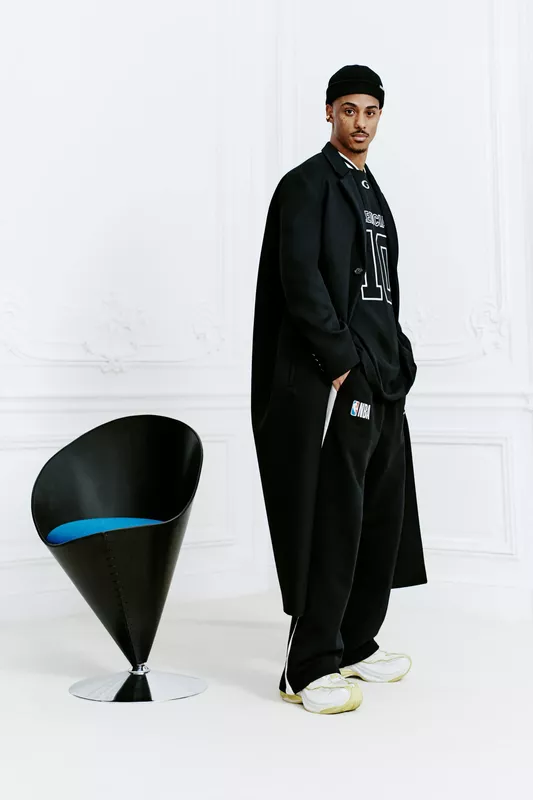 Стильный черный наряд с спортивным акцентом, длинный плащ и кроссовки, подчеркивающие современный городской стиль