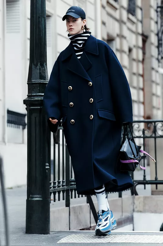 Объемный темно-синий пальто с золотыми пуговицами и полосатым свитером, создающий элегантный городской стиль