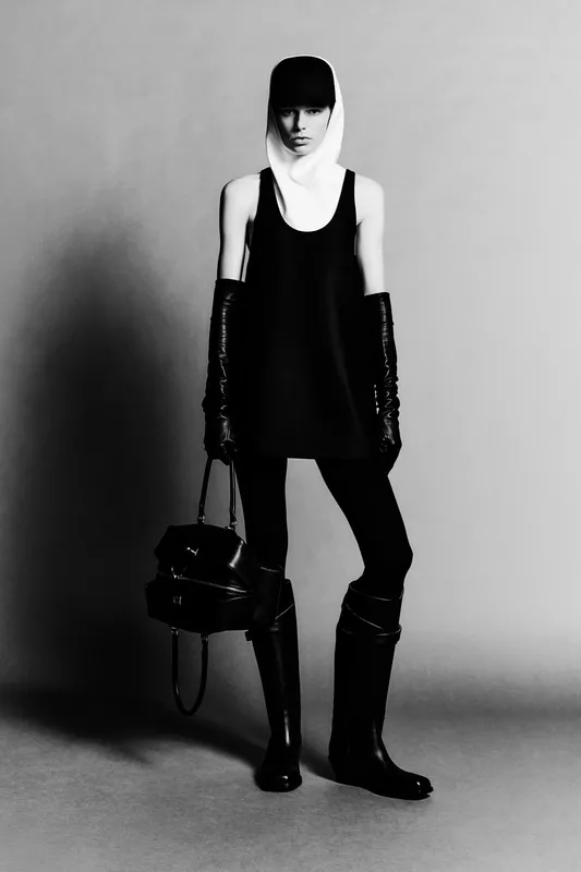 Минималистичное черное платье с белым капюшоном, длинные перчатки и высокие сапоги создают строгий образ в черно-белой гамме