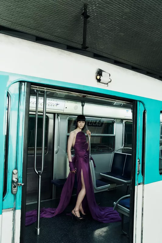 Элегантное фиолетовое платье с высоким разрезом и струящимися элементами, эффектно выделяющееся в вагоне метро