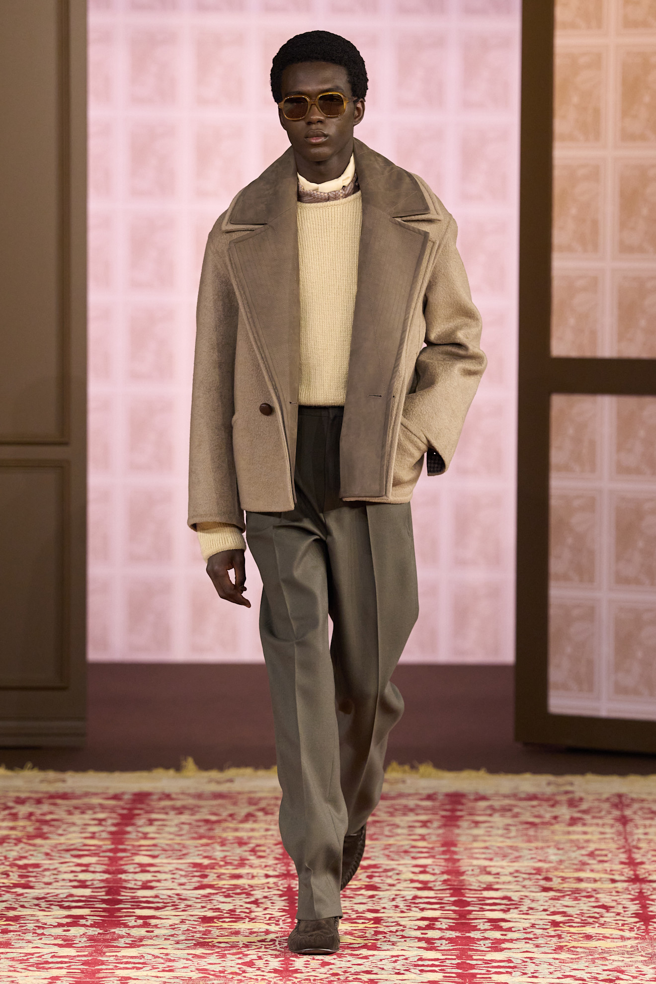 Модель в объемном бежевом пальто и светлом свитере, дополненная стильными очками, создает атмосферу уюта и элегантности