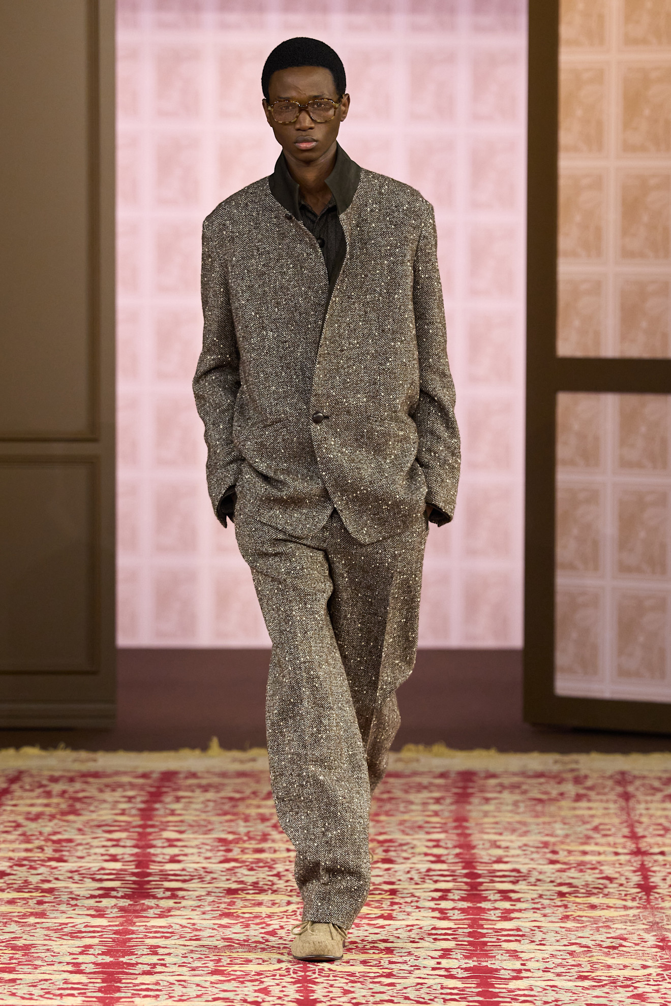 Элегантный костюм из текстурной ткани с блеском, дополненный очками, передает атмосферу утонченной строгости