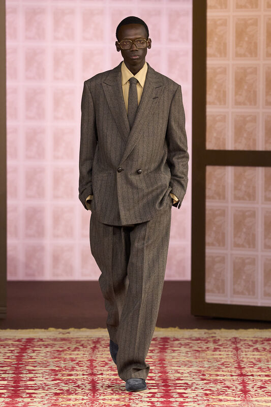 Модель в двойном пиджаке с тонкой полоской и светлой рубашке, создающей контрастный образ