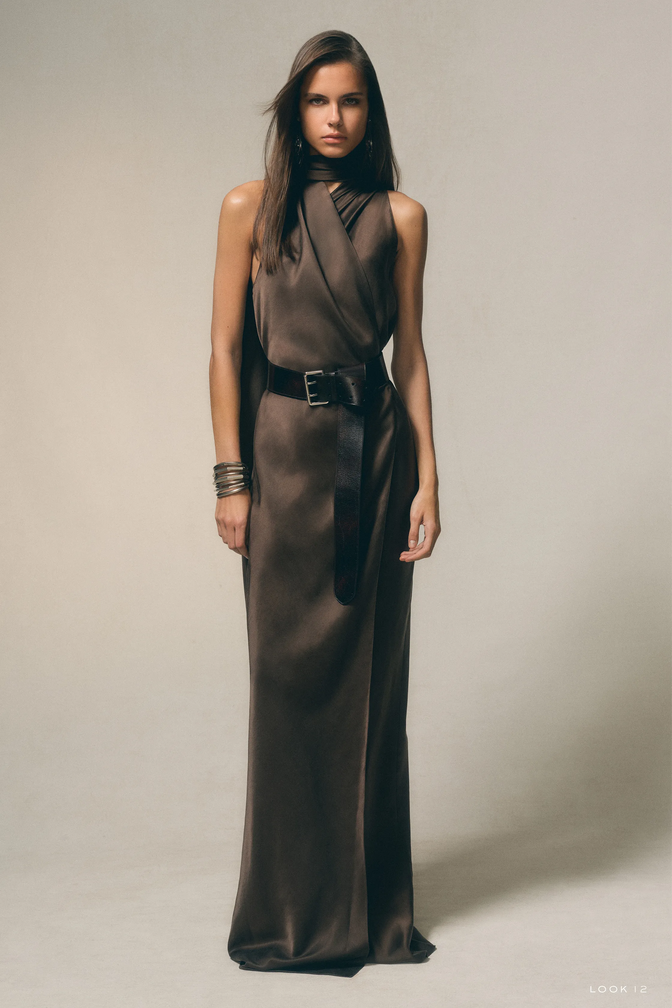 Платье с асимметричным кроем и поясом, выполненное из гладкой ткани, создает эффектный и современный силуэт